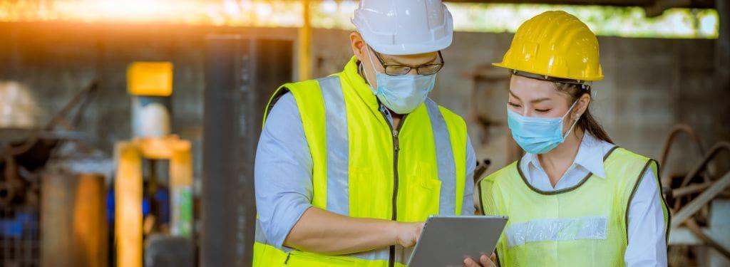 two safety professionals discussing OHS practices using an ISO 45001 software on a tablet|BrightSafe|eCompliance|SafetyAmp|WHS Monitor|MyHRToolkit
