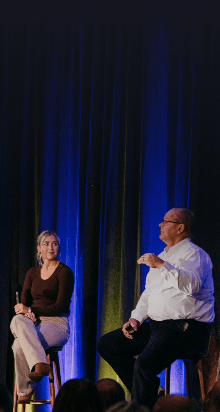 Speakers on stage at an event with blue curtain backdrop