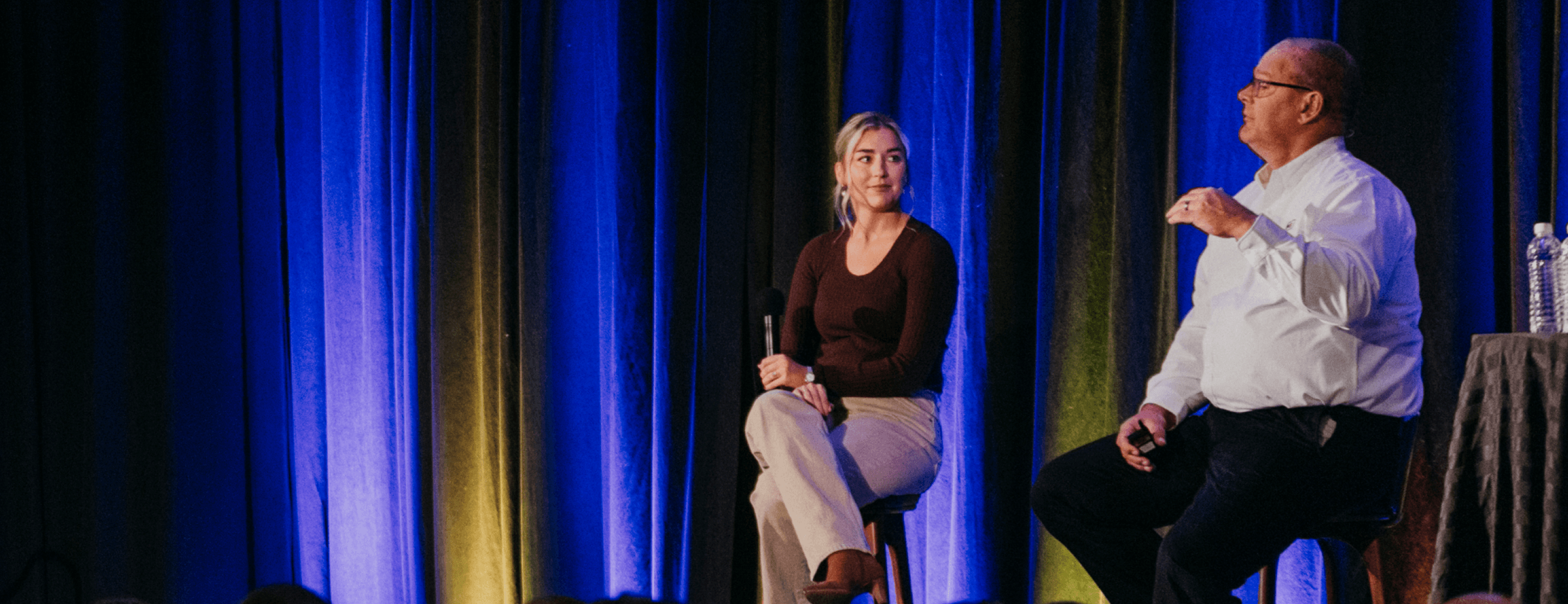 Speakers on stage at an event with blue curtain backdrop