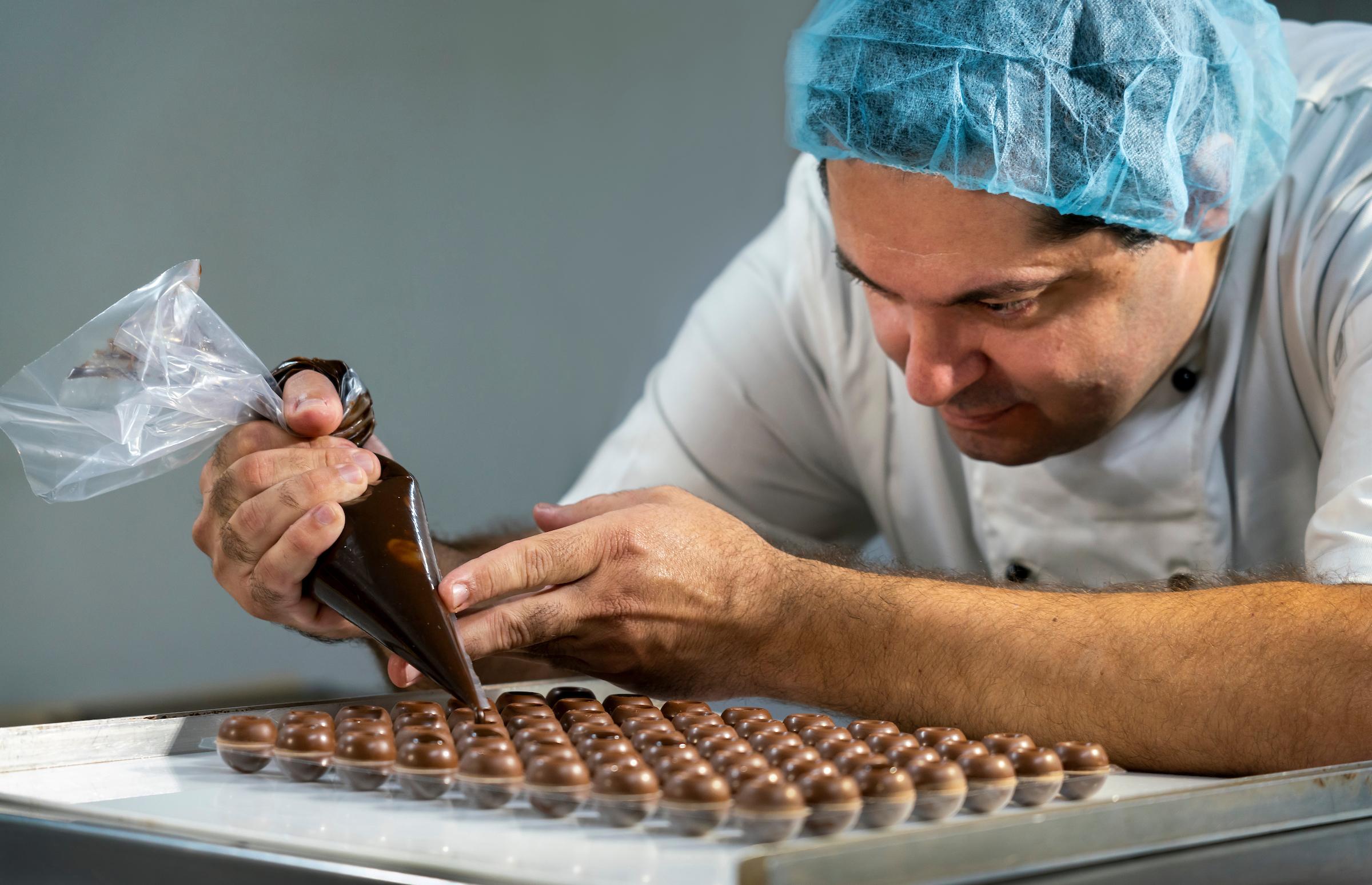 Davies Chocolates worker piping liquid chocolate onto chocolates