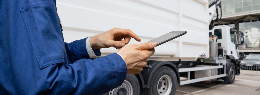 fleet manager using a waste management fleet software on their tablet while outside