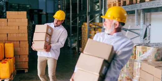 deux travailleurs rencontrant des risques ergonomiques au travail lors du transport et du transfert de cartons dans un entrepôt