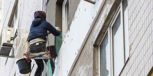 a worker with proper harness while working on windows to avoid OSHA violations on work safety