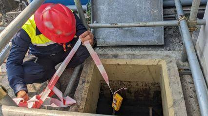 worker helping another worker enter a confined space after signing a permit template|Confined Space Permit Template Sample Report|Confined Space Permit Template