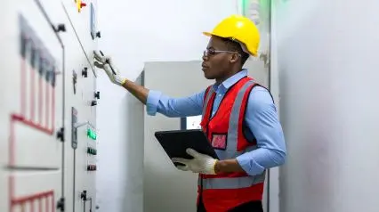 an electrical safety engineer checking controls while reviewing an electrical work permit checklist on a tablet|Electrical Work Permit Checklist Sample Report|Electrical Work Permit Checklist