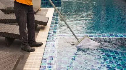 a professional cleaning a pool as part of the daily tasks listed in a pool maintenance checklist|Pool Maintenance Checklist Sample Report|Lista de comprobación del mantenimiento diario de la piscina