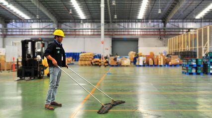 person cleaning a warehouse with a checklist