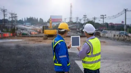 two construction engineers conducting an excavation safety check using a tablet device