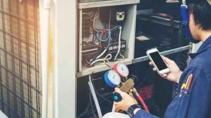 Trabajador inspeccionando una unidad de HVAC mediante un dispositivo móvil