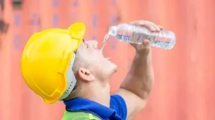 trabajador de la construcción bebiendo agua debido al calor bajo el sol