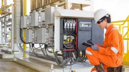 an electrician carefully working around electrical hazards while wearing proper PPE