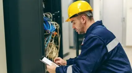 a technician conducting maintenance on electrical systems while checking things off on an electrical maintenance checklist using a tablet device|Electrical Maintenance Checklist Sample Report|Electrical Maintenance Checklist