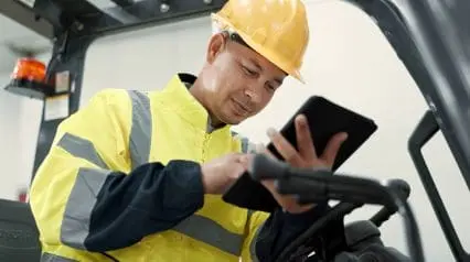 a technician conducting forklift maintenance while checking things off on a forklift maintenance checklist using a tablet device|Forklift Maintenance Checklist|Forklift Maintenance Checklist Sample Report