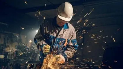 metalworker processes metal with an angle grinder