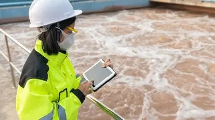 a water treatment engineer using a tablet in inspecting the water treatment plant