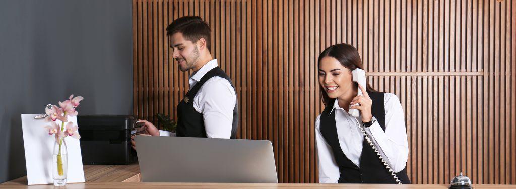 two receptionists managing resort inquiries and reservations using a resort management software on a desktop