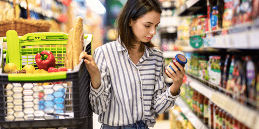 woman checking food product label in grocery