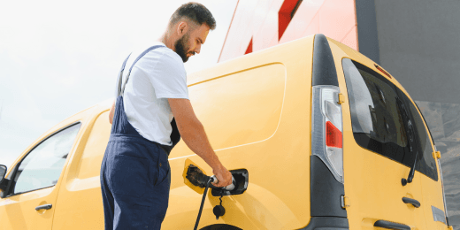 A technician plugging a charging cable into a yellow electric delivery van to demonstrate ISO 15118 communication standards.