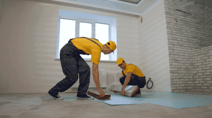 entrepreneurs remplaçant des carreaux de sol pour une rénovation