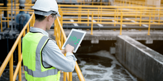 A worker inspects a sewage water treatment facility using a digital tablet.