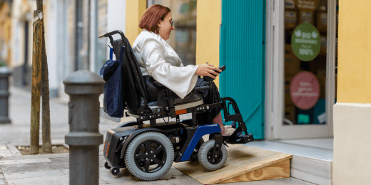 Woman using wheelchair entering store via ramp.