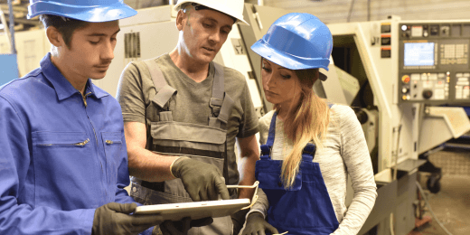 Manufacturing workers huddled together in conversation with a tablet in hand