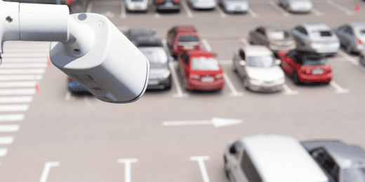 Parking lot security camera overlooking a parking space with multiple parked cars.