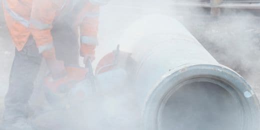 travailleur de la construction découpant un tuyau fabriqué avec de la silice et exposé à ses fumées