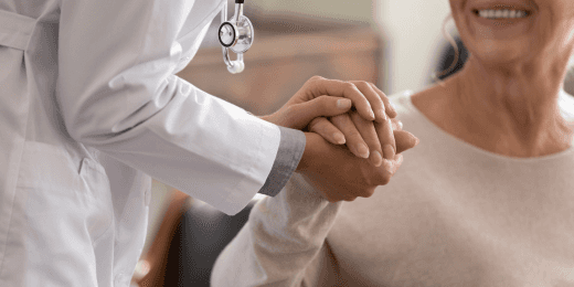 A doctor holding an elderly woman's hand.