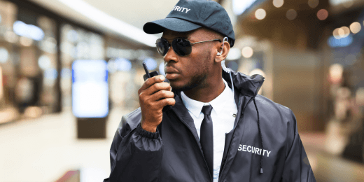 Security guard in uniform using a radio inside a building.