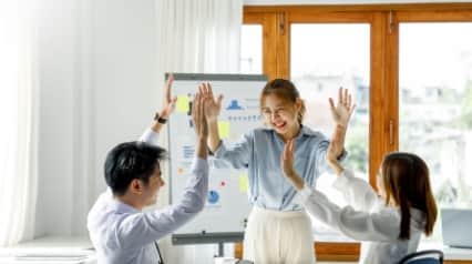 Employee development session with one team lead and two team members highfiving