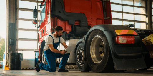 A mechanic inspecting the tires of a truck with his tablet.