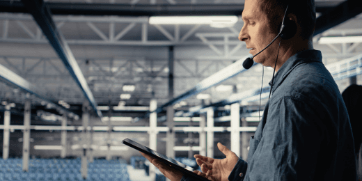 A technician reviews secure data on a mobile device, illustrating the importance of cybersecurity for manufacturing in a large-scale factory setting.