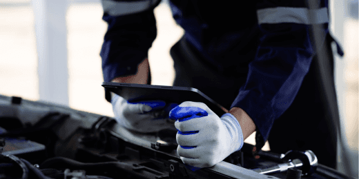 Auto mechanic using a tablet while lubricating a car engine.