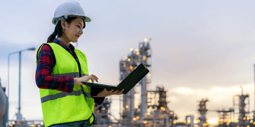 Engineer inspecting oil refinery using laptop