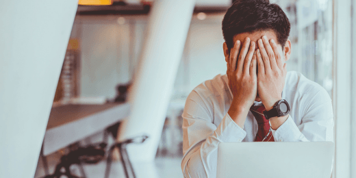A stressed man with his hands over his face.