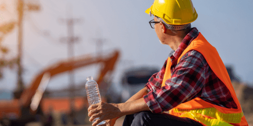 A construction worker resting with a bottle of water because of the extreme heat.