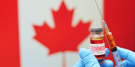 A doctor holding a vaccine vial and a syringe , with a Canadian flag at the back