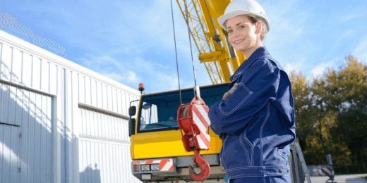 A female safety inspector in a hard hat stands confidently in front of heavy equipment, representing the importance of a mobile crane inspection checklist.