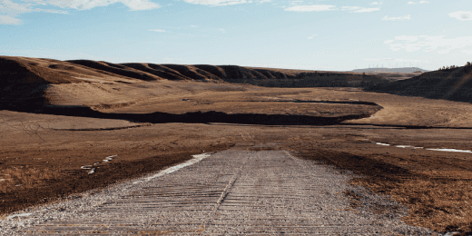 A dirt road leading to a dried up lake.