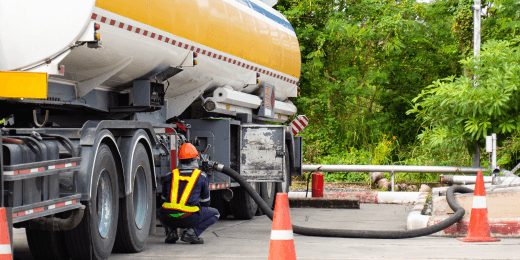 Worker refueling from a fuel tanker truck.