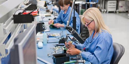 trabajadores que ensamblan piezas de un dispositivo electrónico cumpliendo la normativa rohs