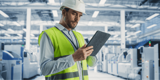 A manufacturing inspection officer, looking at his tablet for equipment maintenance,