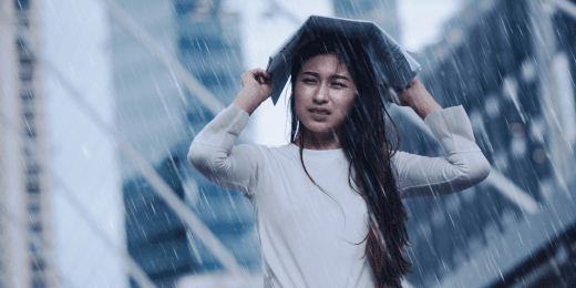 A woman, drenched in water, using a newspaper as an umbrella during a storm.