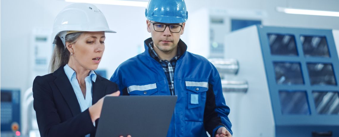 two quality managers discussing ISO 9001 requirements using a laptop