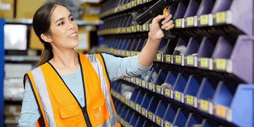 A technician scanning inventory bins with a barcode scanner in a parts storage area.