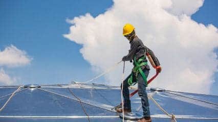 worker on a roof fixing his fall restraint sytstem