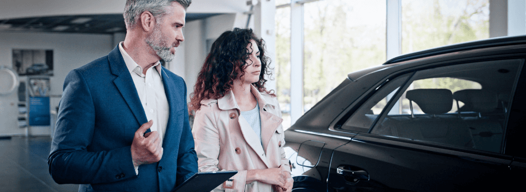 Car dealership representative showing a vehicle to a potential customer.