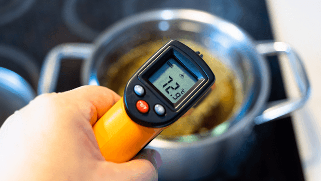 A kitchen staff member is checking food thermometer readings to be entered into a thermometer calibration log template.