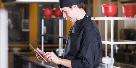 chef referring to kitchen worker safety guidelines on a tablet